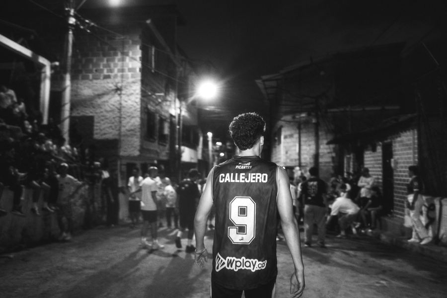 Un jugador con la camiseta de Callejero FC, de espaldas, entrando a la cancha por una calle de la comuna
