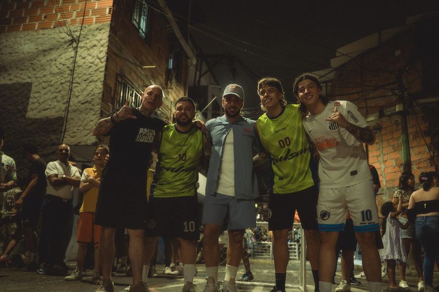 Los dos equipos abrazados en fila sobre una calle empinada del barrio, al final del partido