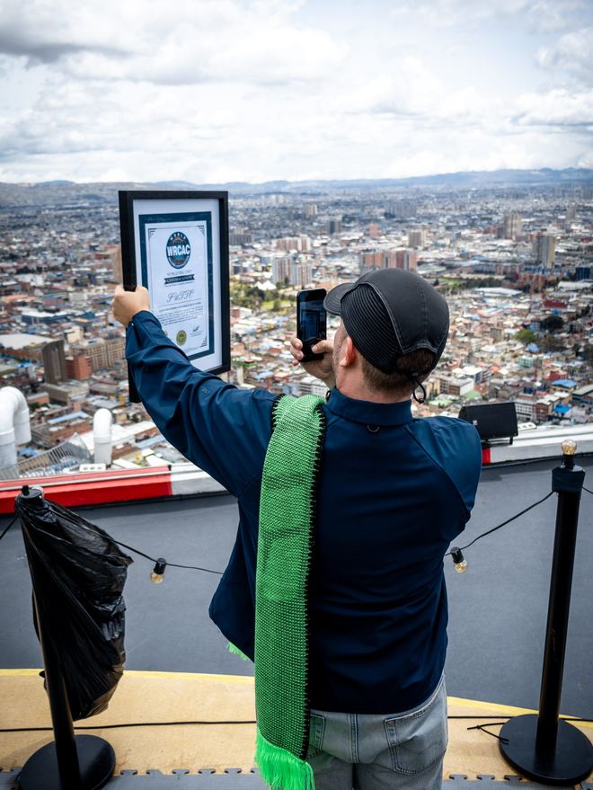 El certificado del récord en alto sobre el borde de la torre, con Bogotá extendida 196 metros más abajo