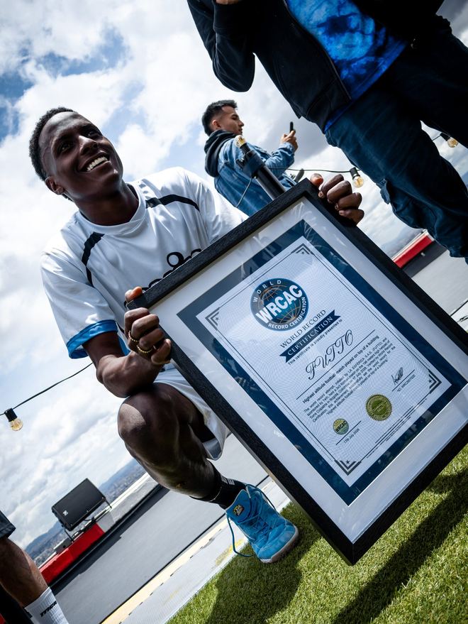 Un jugador sostiene el certificado de la WRCAC que acredita el partido de fútbol más alto del mundo